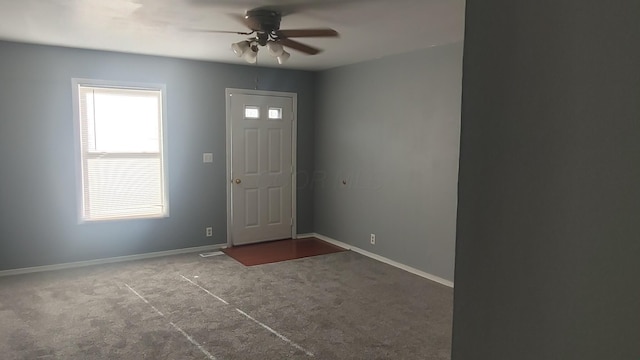 entryway with baseboards, a ceiling fan, and dark colored carpet