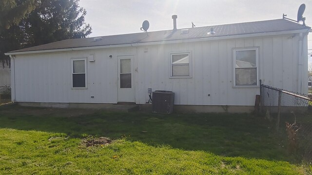 rear view of property with a lawn and central air condition unit