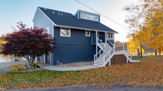 301 John St, Belpre, OH 45714 - view of front of property with roof with shingles, stairs, a front lawn, stone siding, and covered porch