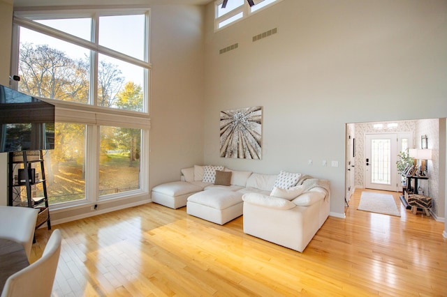 301 John St, Belpre, OH 45714 - living area with visible vents, baseboards, a high ceiling, and wood finished floors