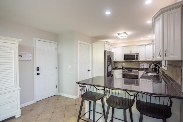 301 John St, Belpre, OH 45714 - kitchen featuring decorative backsplash, appliances with stainless steel finishes, a sink, baseboards, and a peninsula