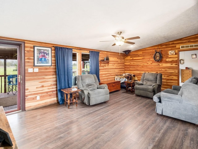 living area featuring wooden walls, ceiling fan, wood finished floors, and lofted ceiling