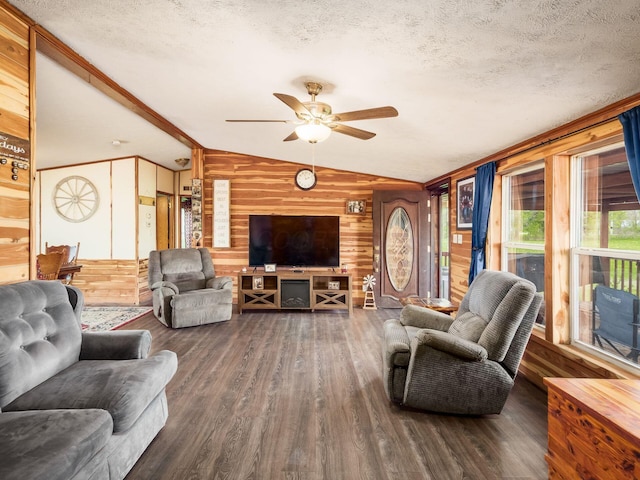 living area featuring ceiling fan, a textured ceiling, wood walls, wood finished floors, and lofted ceiling