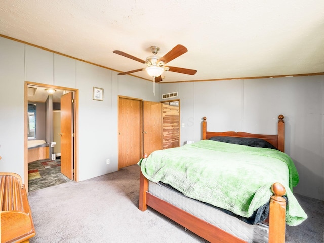 carpeted bedroom featuring a ceiling fan, visible vents, ornamental molding, and ensuite bath