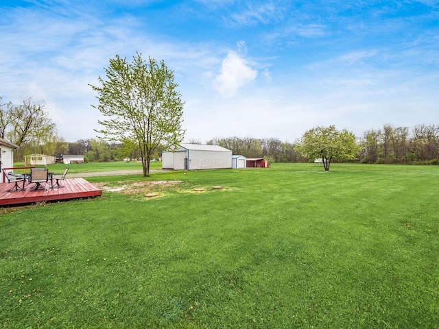 view of yard with a deck, an outbuilding, and outdoor dining space