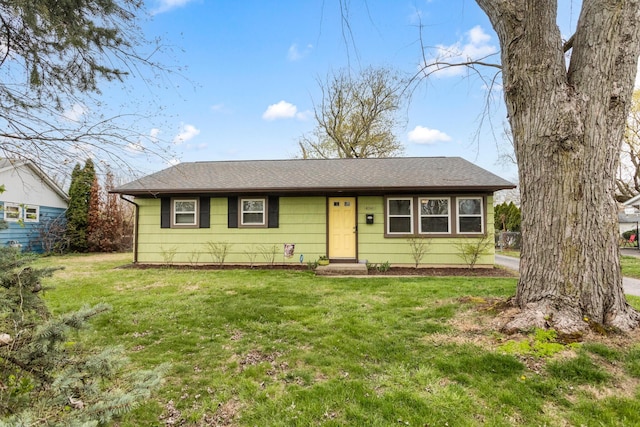ranch-style home featuring a shingled roof and a front yard