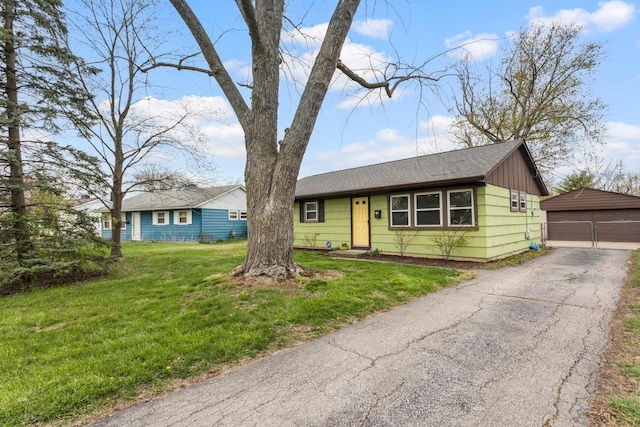 ranch-style house with a detached garage, an outdoor structure, and a front lawn