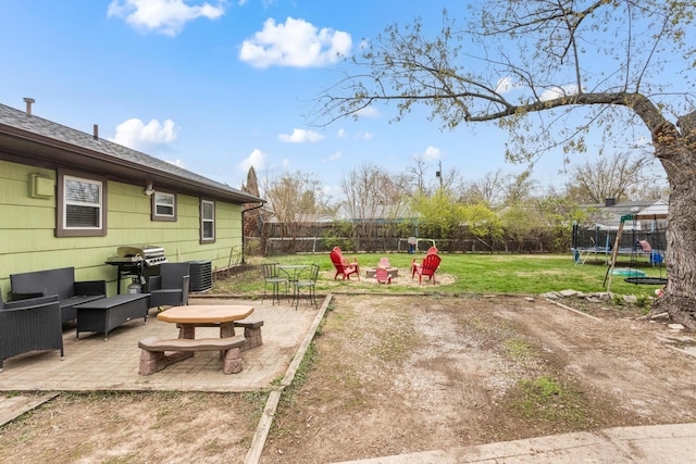 view of yard with a patio, a fenced backyard, a trampoline, and an outdoor living space with a fire pit