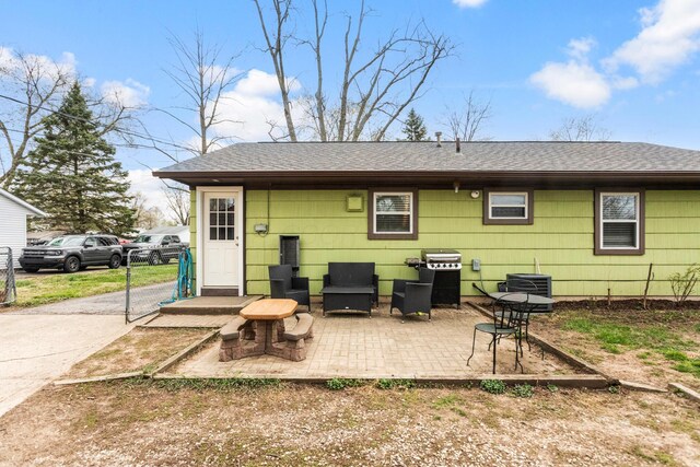 rear view of property with a patio, central AC unit, and a shingled roof