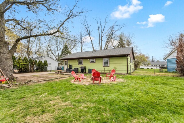 rear view of property with a yard, fence, a fire pit, and a patio area