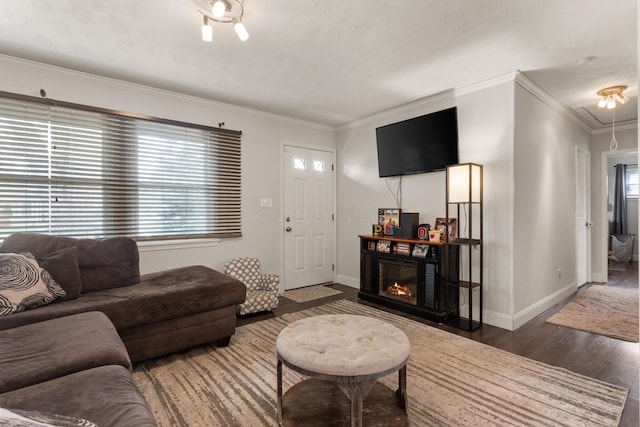 living room with crown molding, baseboards, attic access, and wood finished floors