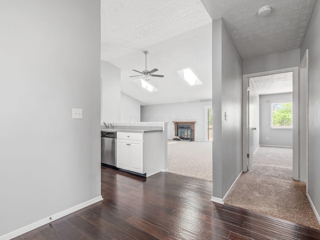 kitchen with stainless steel dishwasher, ceiling fan, open floor plan, and baseboards