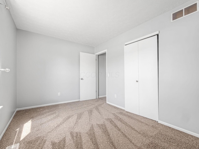 unfurnished bedroom featuring carpet floors, baseboards, visible vents, and a closet