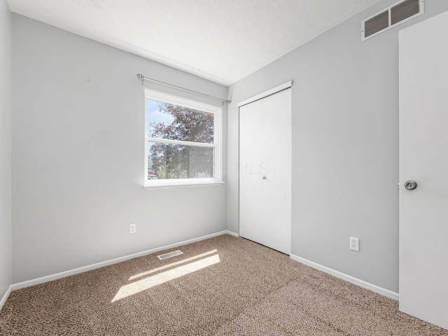 spare room featuring carpet floors, baseboards, and visible vents