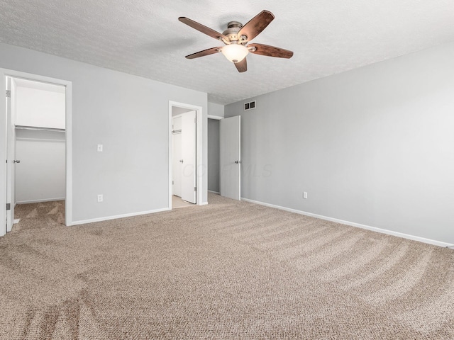 unfurnished bedroom with baseboards, visible vents, light carpet, and a spacious closet