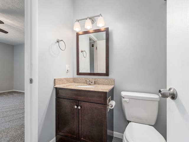 bathroom with vanity, a textured ceiling, baseboards, and toilet