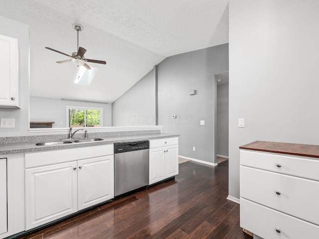 kitchen featuring ceiling fan, dark wood finished floors, dishwasher, a sink, and lofted ceiling with skylight