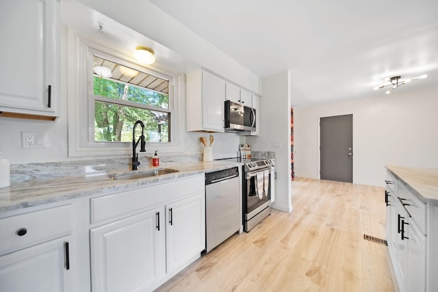 4959 Hughes Rd, Prospect, OH 43342 - kitchen with stainless steel appliances, a sink, light wood-style floors, and white cabinetry