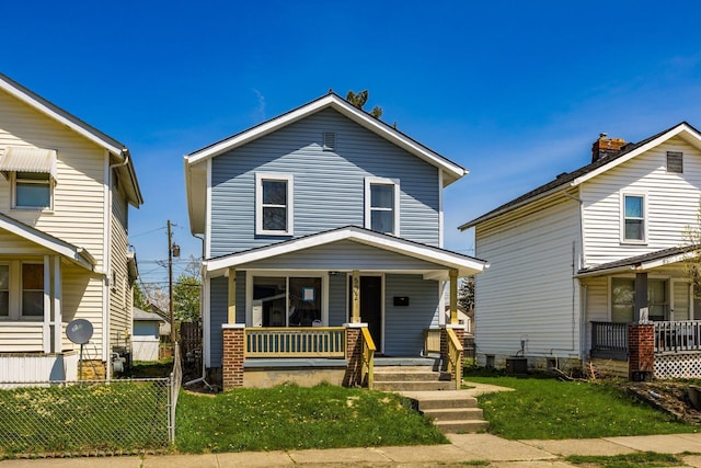 view of front of home featuring covered porch, fence, and a front yard