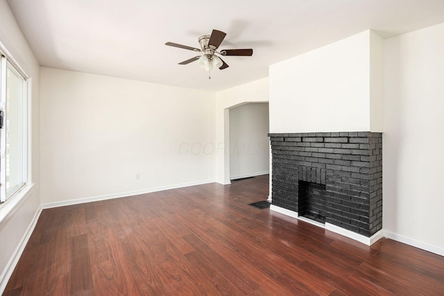 unfurnished living room featuring baseboards, dark wood-style flooring, ceiling fan, and a fireplace