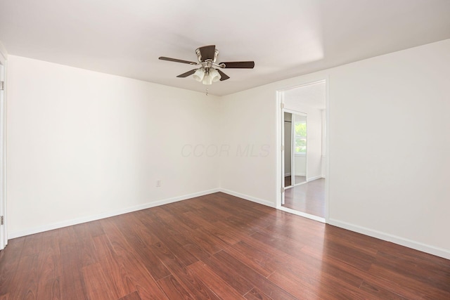 spare room with dark wood-style floors, baseboards, and ceiling fan