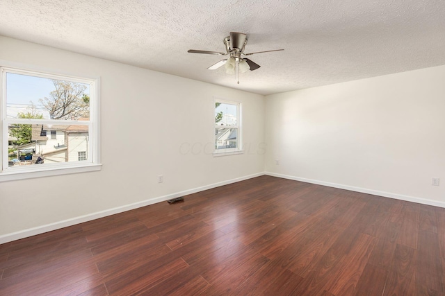 empty room with wood finished floors, baseboards, visible vents, a ceiling fan, and a textured ceiling