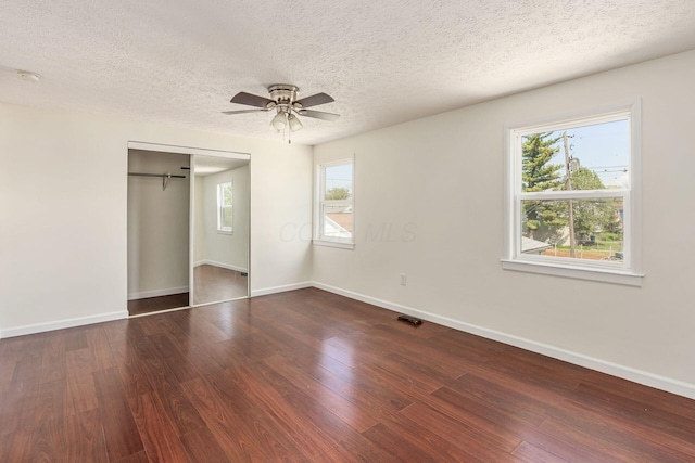 unfurnished bedroom with multiple windows, wood finished floors, and a closet