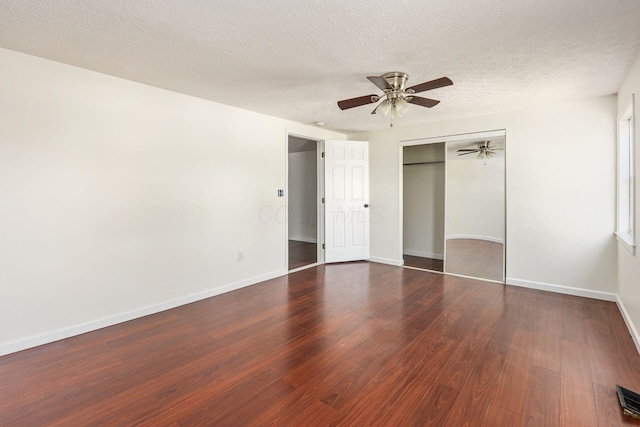 unfurnished bedroom with a textured ceiling, wood finished floors, baseboards, and a closet