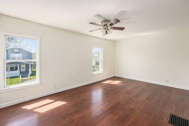empty room with visible vents, baseboards, and dark wood-type flooring