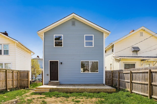 rear view of house featuring a wooden deck and a fenced backyard