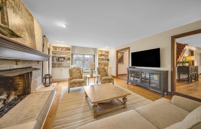 living room featuring light wood-style floors, a brick fireplace, and built in features