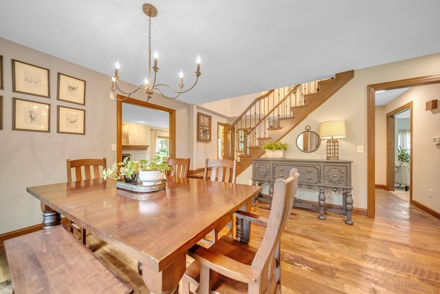 dining room featuring baseboards, stairway, a chandelier, and light wood-style floors