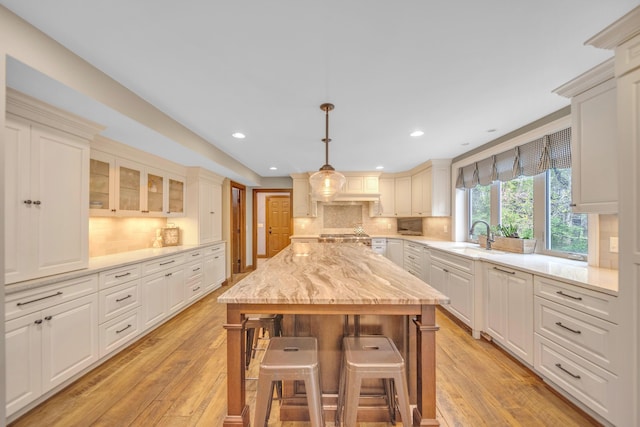 kitchen with tasteful backsplash, light wood-type flooring, a kitchen breakfast bar, and a sink