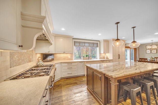 kitchen featuring light wood finished floors, a sink, a kitchen bar, range, and a kitchen island