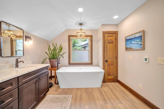 bathroom with recessed lighting, vanity, wood finished floors, baseboards, and a soaking tub