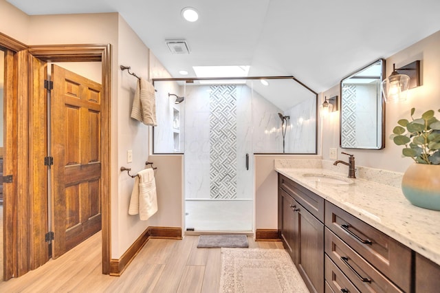 full bath with a tile shower, visible vents, wood finished floors, and vanity