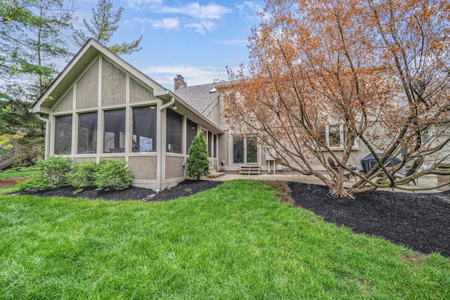 rear view of house with a sunroom, a lawn, and a chimney