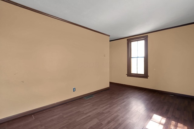 spare room with dark wood-style flooring, baseboards, visible vents, and ornamental molding