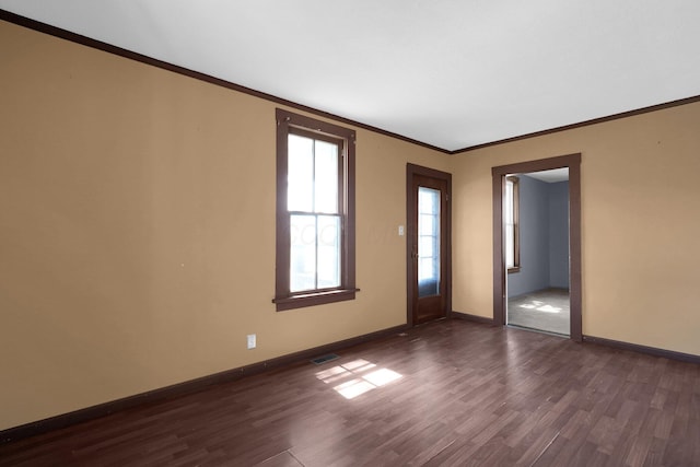 unfurnished room featuring crown molding, baseboards, dark wood finished floors, and visible vents