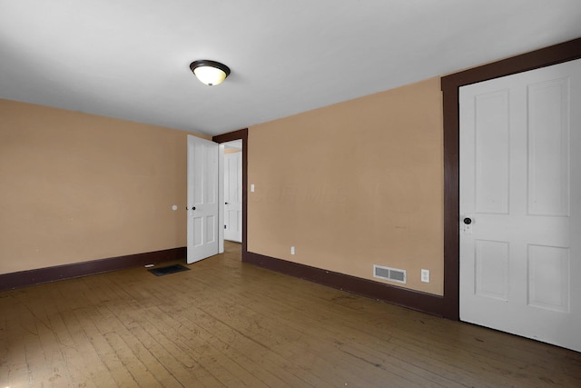 unfurnished room featuring baseboards, visible vents, and hardwood / wood-style floors