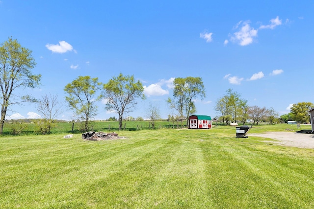 view of yard with a barn, a rural view, and an outbuilding