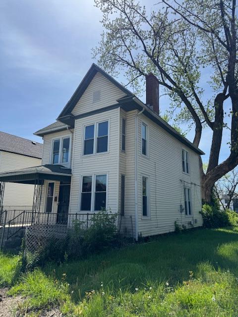 view of side of home featuring a chimney and a porch