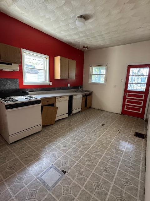 kitchen with light countertops, a sink, under cabinet range hood, and white appliances