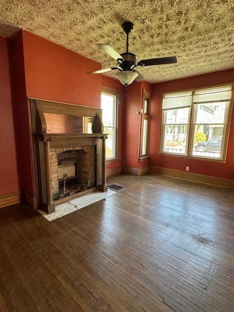 unfurnished living room with a ceiling fan, hardwood / wood-style floors, a fireplace with flush hearth, and baseboards