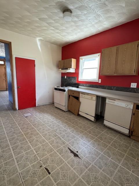 kitchen featuring white appliances, range hood, and light countertops