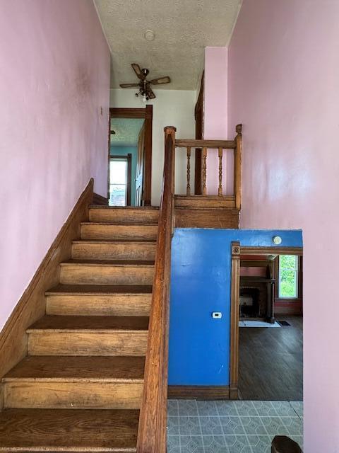 staircase featuring a textured ceiling and wood finished floors