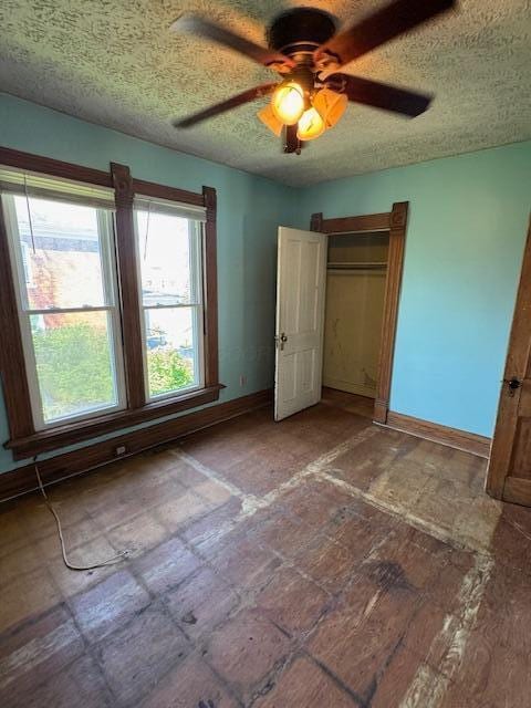 unfurnished bedroom with baseboards, ceiling fan, a textured ceiling, and a closet