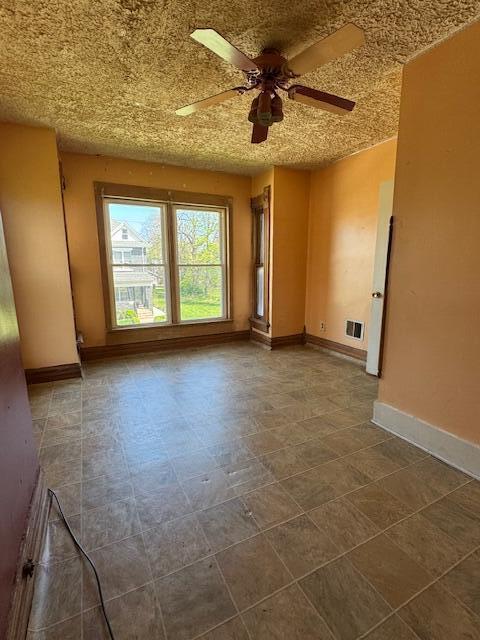 empty room with visible vents, ceiling fan, and baseboards