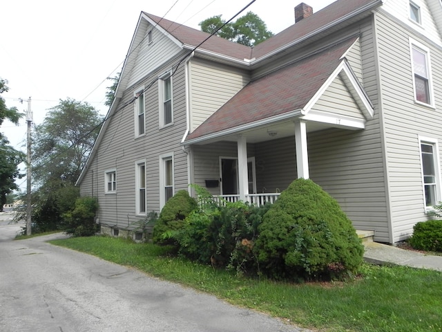 view of property exterior featuring a porch and a chimney