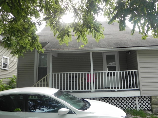 rear view of property featuring roof with shingles and covered porch